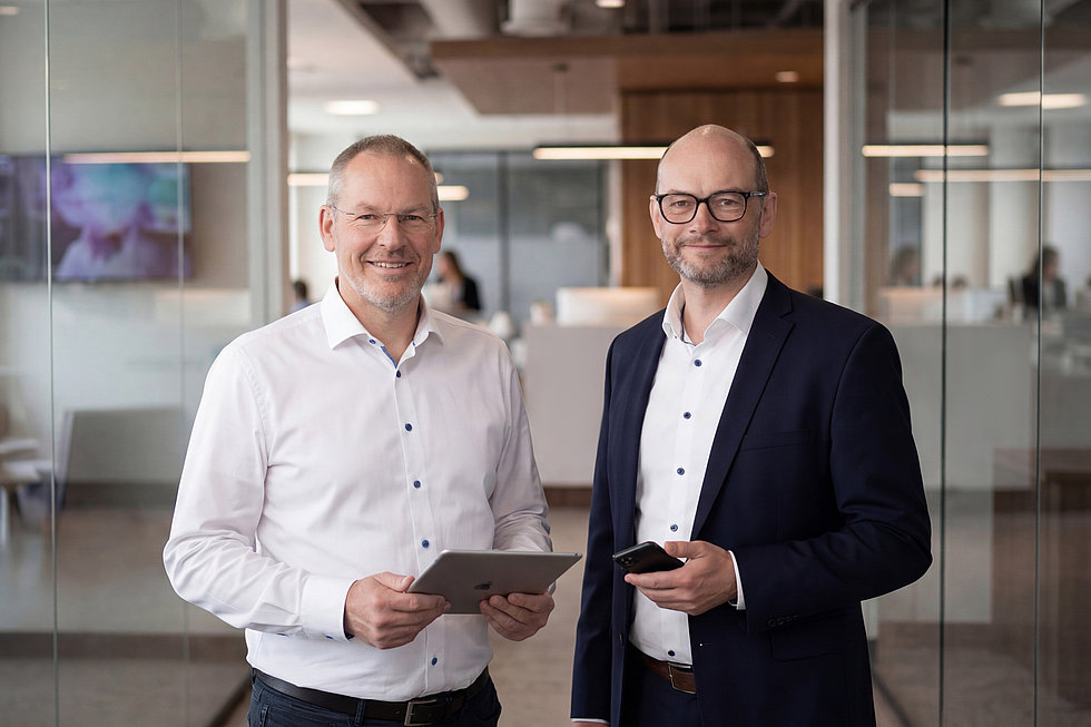 Die Geschäftsführung von NordConnect posiert vor modernem Bürohintergrund.
